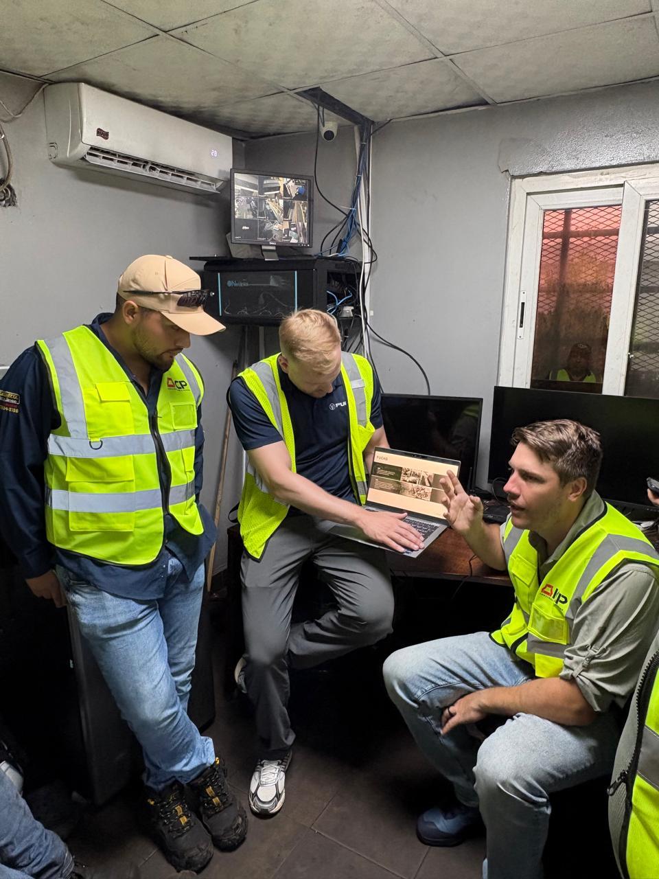 Fuchs representative showing a laptop with Fuchs documentation to two men in ICP safety vests in the yard office