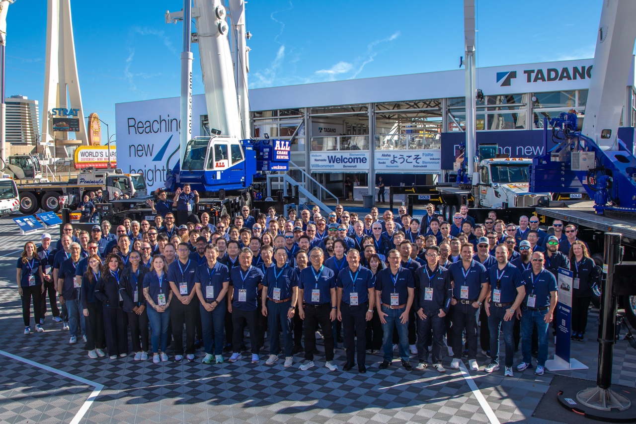 Large group of Tadano staff posing in front of cranes on the Tadano stand at CONEXPO 2026